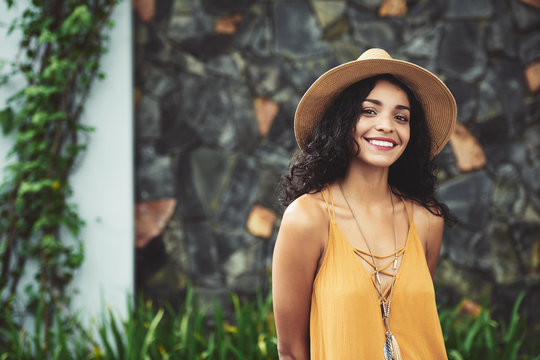 Very beautiful young Hispanic woman in straw hat smiling at camera