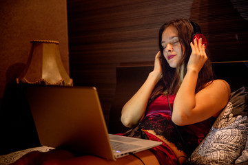 young woman listens to music in headphones from laptop