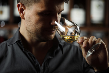 Close up of sommelier man sniffing wine in glass © Ilshat