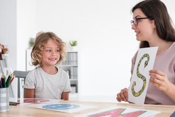 Speech therapist teaching pronunciation to a little kid using colorful pictures - obrazy, fototapety, plakaty
