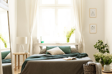 Bedroom interior in nature colors with big bed, gray and green linen and pillows, fresh meadow...