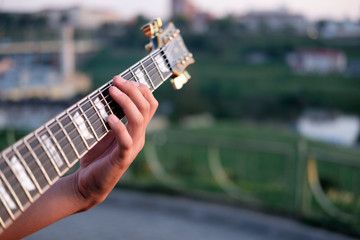 hand of guitarist perfoming chord on a grif of electric guitar, outdoors