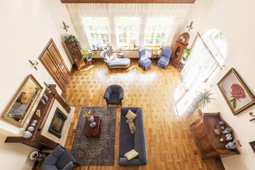 Top view of a spacious living room interior with a fireplace, blue set on sofa, chairs and...