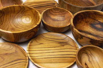Wooden utensils for the kitchen, bowls, plates on a black background. The concept of natural dishes, a healthy lifestyle. Texture of wood. Wooden eco-ware