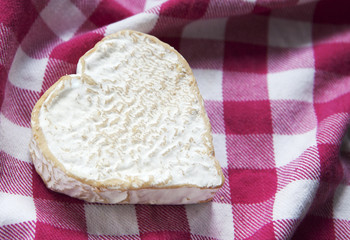 fromage en coeur sur un torchon a carreaux 