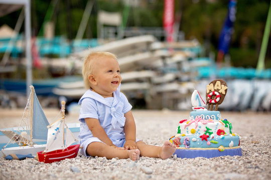 Sweet baby boy, celebrating on the beach first birthday with sea theme cake and decoration