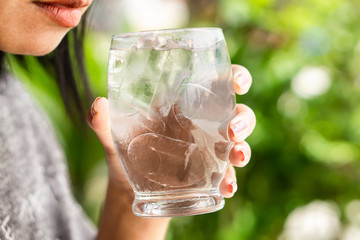 woman drinking cold water with ice in glass in morning