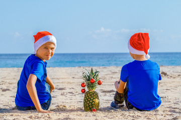 Kids in red Santa hats having fun at sea beach during Christmas vacation
