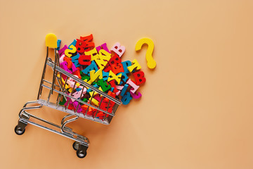Mini shopping cart or trolley full of English letters on beige color background