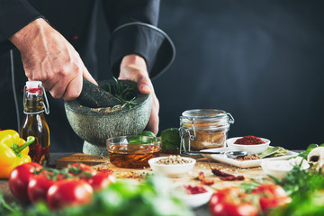 Chef grinding herbs in a pestle and mortar