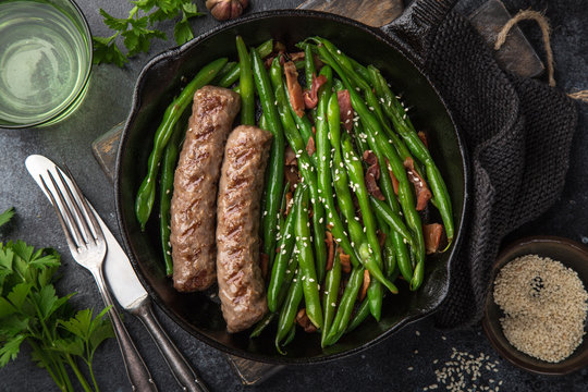 roasted green bean with bacon and sausages on cast iron pan