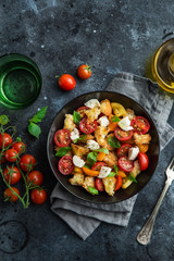panzanella, traditional italian tomato, mozzarella and bread salad in black bowl, top view