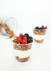 Breakfast from fresh natural yogurt with homemade granola and berries in glass on textile background
