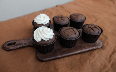 Chocolate cupcakes with cream cheese on a wooden board