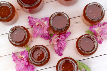 Fresh honey in glass jar on light white wooden background.