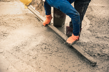 Man sitting and using a wooden spatula for cement after Pouring ready-mixed concrete on steel...