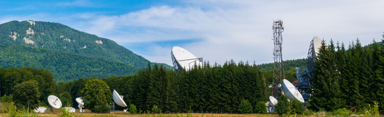 Big satellite dish antennas hidden in green pine tree forest. Satellite Communication Center in Cheia, Prahova, Romania