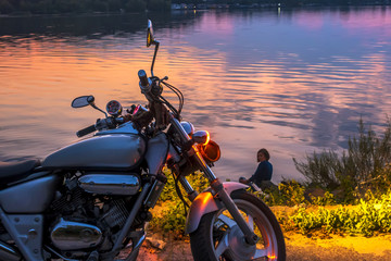 Naklejka premium Old retro motorcycle by the river on sunset background