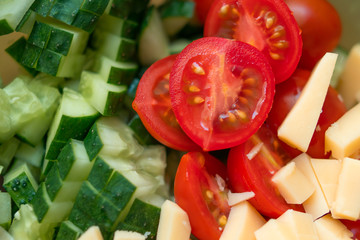 Tomatoes, cucumbers and pieces of cheese assorted in salad. Healthy food, diet concept