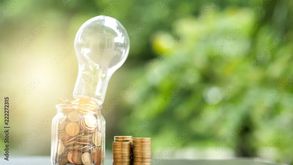 Wall mural energy saving. stacks of coins in bottle and tree growing in light bulb and motion tree nature backg