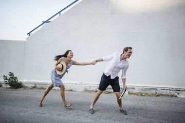 Young couple fooling around but against a white building