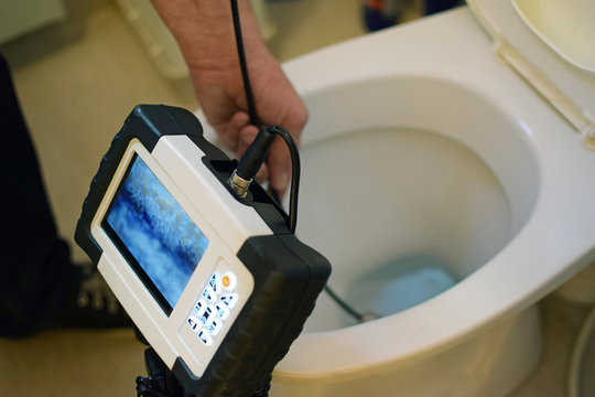 Checking clogged toilet pipe with inspection camera.