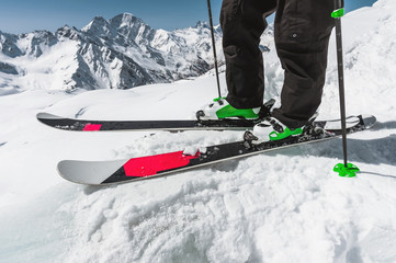 Foot athlete skier in professional ski boots on snow. A close-up of the skis on the athlete's legs...