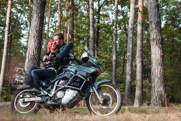 Fototapeta na wymiar Outdoor shot of happy young romantic couple with big motorcycle for tourism and travel. autumn forest background, traveling together, off road, red hair girl