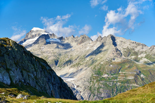 Blick vom Grimselgebiet zum schneebedeckten Galenstock und die Furkapassstrasse mit dem Hotel Belv&eacute;d&egrave;re, links die Zunge des Rhonegletschers, blauer Himmel mit einigen Wolken