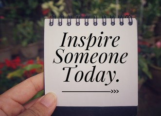 Motivational and inspirational quote - ‘Inspire someone today’ written on a notebook. With...