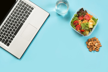 Healthy business lunch in office, salad, almonds, water on blue. Top view with copy space. Concept...