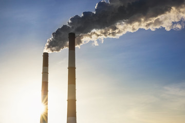 Smoking pipes making clouds against blue sky background. Dioxide air contamination. Environmental...