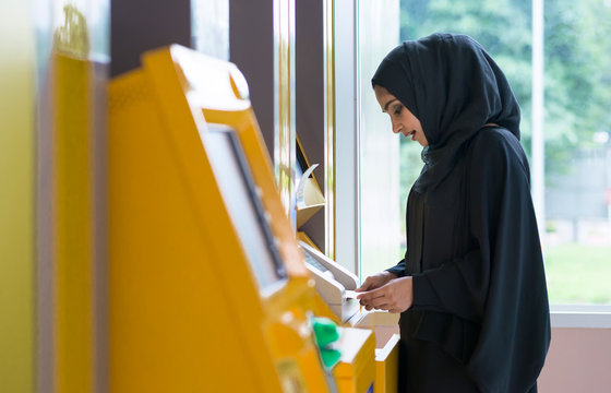 Arab Woman And Automated Teller Machine . Woman Withdrawing Money Or Checking Account Balance.