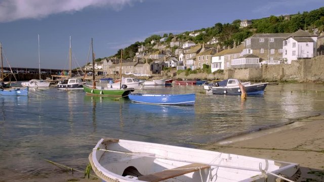 Camera rises behind small boat to reveal harbour of Mousehole in Cornwall 