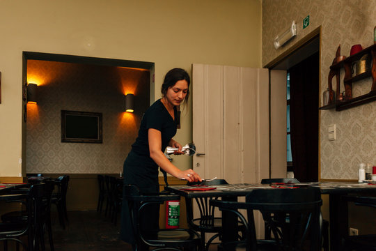 A Young Good-looking Maid, Is Busy Preparing Tables In The Dining Room Of A Hipster Restaurant