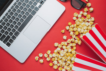 Glasses and popcorn with keyboard on a red background top view