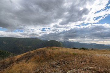 Dramatic sky with the sun rising through the clouds on the Way of Saint James (Camino de Santiago) in El Bierzo area between Foncebadon and Manjarin, in Leon, Spain.
