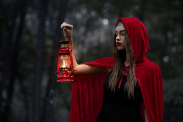 mystic girl walking in dark forest with kerosene lamp