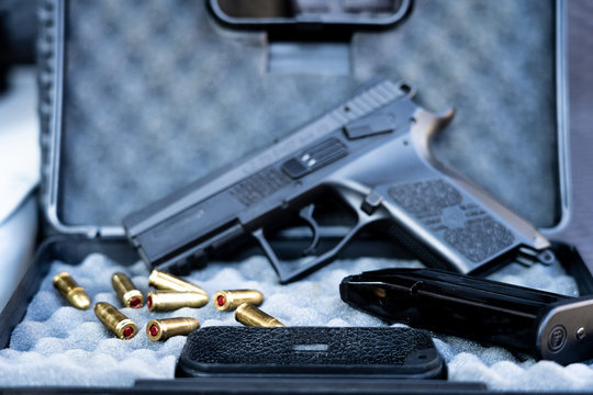 Close up view of bullets and handgun. Small black pistol next to a 9 mm bullets and a magazine. Shallow depth of field.