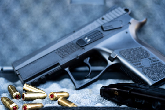 Close up view of bullets and handgun. Small black pistol next to a 9 mm bullets and a magazine. Shallow depth of field.