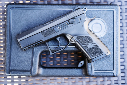 Top view of handgun. Small black pistol loaded with a magazine on a carrying box.