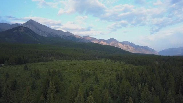 Jasper Banff National Park and mountain view by drone. Wide open landscape over national forest on sunny evening . Alberta Canada aerial view from above. Hugh pine trees and wildlife meadows below
