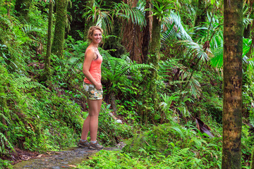 Naklejka na ściany i meble Adventurous and stunning young woman hiking in the beautiful jungle of the El Yunque national forest in Puerto Rico
