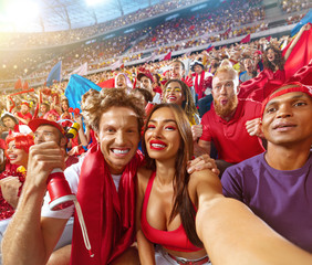 Fototapeta Young sport supporter happy fans at stadium. Beautiful man and woman support the football team during the match and making selfie photo obraz