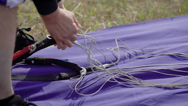Close up shot of a skydiving instructor packing, preparing equipment for the jumping, parachute straps.