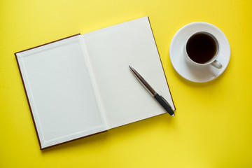 Notepad for text and Cup of coffee yellow table with copy space. Education and office concept.