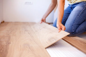 Obraz na płótnie Canvas Selective focus photo of a young woman installing laminate flooring. Home improvement and renovation concept