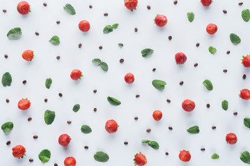 top view of ripe strawberries with mint leaves and coffee beans on white tabletop