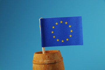 A beautiful blue flag of europe on wooden stick in wooden barrel on blue background