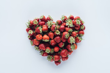 top view of heart shape sign made of ripe strawberries on white surface